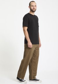 Sort kortærmet t-shirt med rund hals, parret med brune corduroy bukser med vidde og sorte sneakers. Glat stof, afslappet pasform.