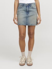 Denim minikjol i ljusblått, med en åtsittande design, fem fickor och knappstängning. Bärs med beige sneakers och ljusa strumpor.