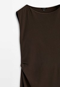 Ruskea hihaton mekko, jossa on pyöreä kaula-aukko, pehmeä rakenne, sivussa laskostus ja löysä malli, joka valuu lempeästi bodista.