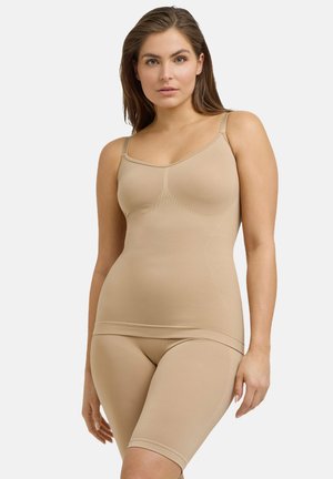 Top in tessuto seamless beige con supporto per reggiseno e pantaloni corti abbinati fino a metà coscia. Tessuto morbido e elasticizzato con una consistenza liscia. Spalline regolabili.