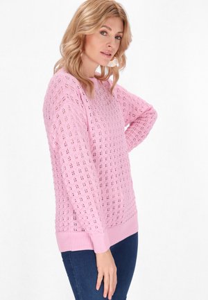 Lyserød strikket sweater med et struktureret, åbent vævemønster. Ribkanter ved ærmer og bund. Bæres sammen med mørke jeans, har lange ærmer og en afslappet pasform.