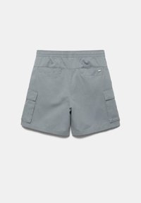 Short gris clair avec taille élastique et deux poches à rabat, vu de dos sur un fond uni.