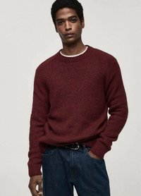 Maroon knit sweater with a crew neckline and ribbed cuffs. Worn over a white shirt, paired with dark denim jeans. Soft texture, casual fit.
