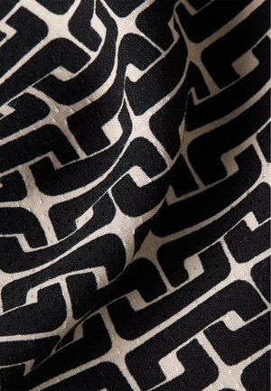Mustekki musta ja kerma kuvioitu kangas, jossa on geometrinen muotoilu. Pintakuvio näyttää sileältä ja siinä on hieman kiiltoa.