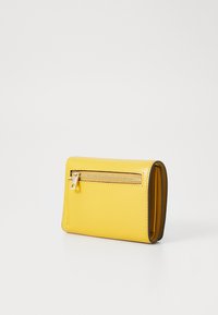 Portefeuille en cuir jaune avec un compartiment zippé, texture lisse et forme rectangulaire aux bords contrastés.
