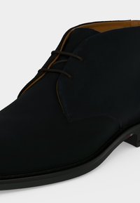 Chaussure habillée noire en cuir à lacets avec une finition lisse et une doublure intérieure marron, montrée de côté et de dessus.