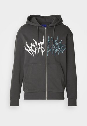 Sweat à capuche noir zippé avec poches avant, capuche à cordon de serrage, et texte graphique en blanc et bleu déchiqueté sur la poitrine.