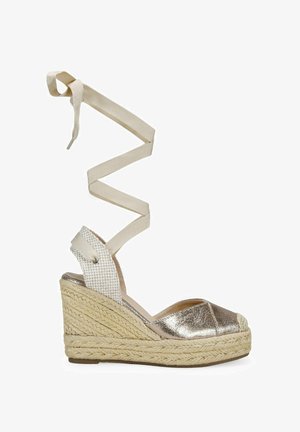 Metallic silver espadrille wedge sandal with textured jute sole, a woven heel, and long beige fabric ankle ties. Open toe design.