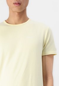 Lichtgele t-shirt met korte mouwen, gemaakt van zacht katoen. Heeft een ronde halslijn en een klein wit "Pepe Jeans" logo op de borst.