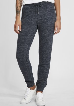 Mørkegrå idretts joggebukser laget av teksturert stoff, med snor i livet og ribbestrikket ankel, kombinert med hvite sneakers.