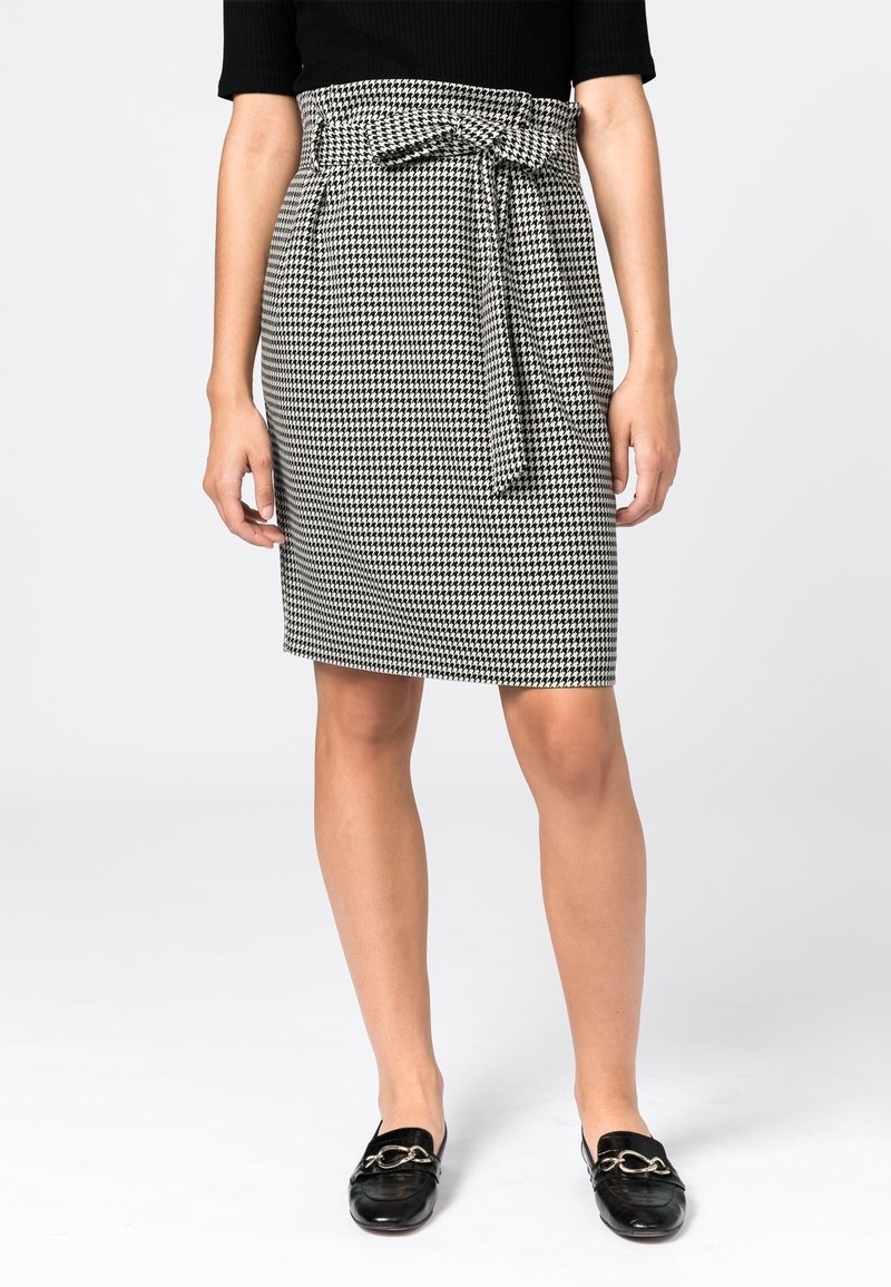 Mustavalkoinen houndstooth-kynähame, jossa on nauhavyötärö, sileä tekstuuri ja suora leikkaus, yhdistettynä mustiin loafereihin.