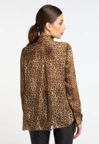 Camicia con stampa leopardata in tessuto leggero e trasparente. Caratterizzata da un colletto alto con volant e maniche lunghe, presenta una linea dritta e un dettaglio con plissé sul retro.