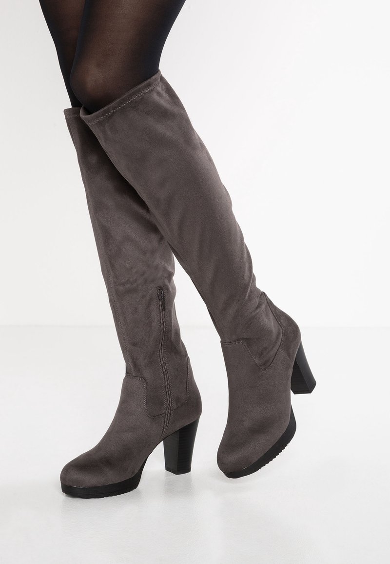Botas gray de ante por encima de la rodilla con tacón cuadrado, que presentan un zipper lateral y una textura suave. Acabadas con detalles de costura minimalista.