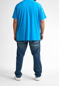 Camiseta de algodón azul claro con un corte relajado, combinada con jeans de mezclilla azul oscuro. Los jeans presentan un corte recto y un ligero desvanecimiento.