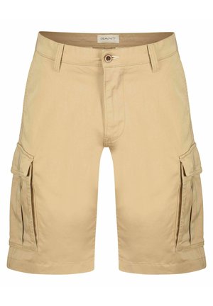 Pantaloni cargo beige in cotone con chiusura a zip e bottone, dotati di tasche laterali e vestibilità comoda. Dettagli includono orli cuciti.