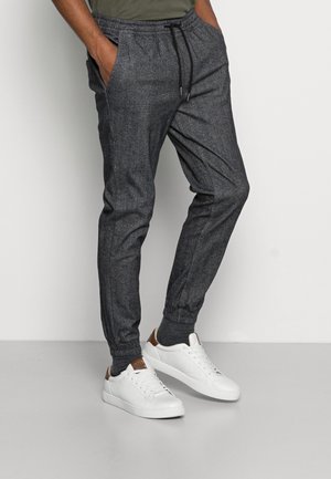 Gray, textured sweatpants with an elastic waistband and side pockets, tapered leg design, paired with white sneakers.