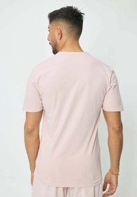 T-shirt rose clair à manches courtes avec col rond, en coton, présentant une texture douce et une coupe décontractée, montré de dos.