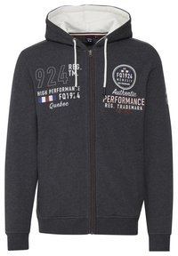 Zip-up dukserica s kapuljačom u tamnosivoj boji, izrađena od flisa. Sadrži bijelu unutrašnjost, otiske logotipa i kontrastne detalje na zatvaraču.