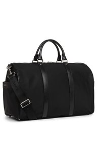 Sac de sport noir en nylon avec des accents en cuir, poignées doubles, bandoulière amovible et quincaillerie argentée pour la fermeture.