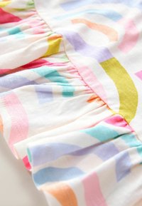 Colorful cotton fabric featuring a white background with large, abstract, multicolored shapes in pink, blue, yellow, and green; ruffled edge.