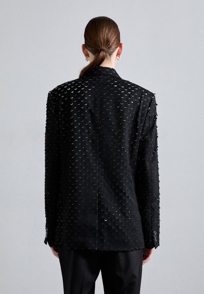 Black blazer with a textured surface made of overlapping circular pieces. Features a tailored fit and single-button cuffs.