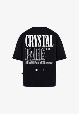 Černé tričko s krátkým rukávem se velkým bílým textem: "CRYSTAL PARIS™" a "MEZINÁRODNÍ ZAREGISTROVANÁ ZNAČKA." Obsahuje malou grafiku francouzské vlajky.