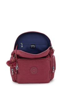 Mörkrosa tygryggsäck med zippered fack, prytt med en plyschapa som nyckelring och en kontrasterande marinblå inredning.