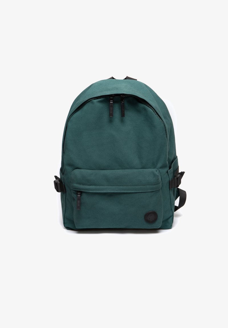 Žalias kanvos kuprinės krepšys su suapvalinta forma, priekinė kišenė, du juodi užtrauktukų laikikliai ir apvalus audinio logotipas apatinėje priekinėje dalyje.