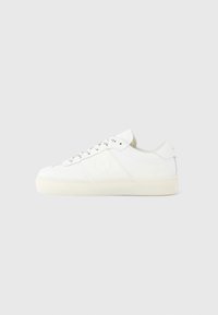 Hvite sneakers med overdel i glatt lær, kontrasterende liskeøyer, rundet tå og en litt gjennomsiktig gummisåle.