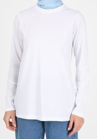 Weißes Langarmshirt mit rundem Ausschnitt, leichtes Material, lockere Passform, kombiniert mit einem hellblauen Halstuch, keine sichtbaren Muster oder Akzente.