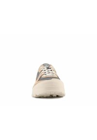 Zapatilla beige y gris con suela gruesa, diseño de cordones y acentos en paneles contrastantes. Tela texturizada y suela de goma visibles.