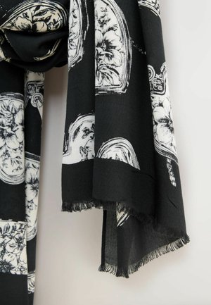 Schwarzer Schal mit weißen Blumen- und Musterdesigns, mit einem Fransenrand entlang der Kanten, aus einem weichen, leichten Stoff gefertigt.