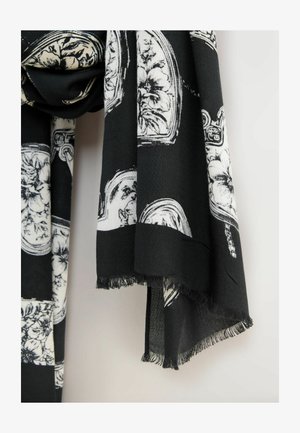 Schwarzer Schal mit weißen Blumen- und Musterdesigns, mit einem Fransenrand entlang der Kanten, aus einem weichen, leichten Stoff gefertigt.