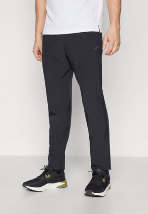 Pantalon de sport noir avec une coupe slim, fabriqué en matière légère. Dispose de poches latérales et d'un logo discret près de la taille.