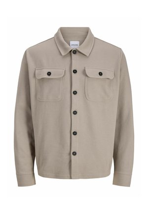 Veste chemise beige clair en tissu texturé, dotée d'un col, de deux poches poitrine et de fermetures à boutons noirs.