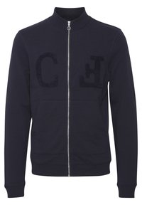 Marineblaue Zip-Jacke mit hohem Kragen, zwei Fronttaschen und strukturierten Buchstaben "C" und "H" auf der Brust. Aus Baumwollmaterial.