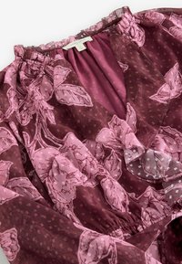 Sraigi burgundi bluzonė su rožinėmis gėlių raštais. Audinys permatomas, su tekstūriniais taškeliais. Savybės: elastingas iškirpimas ir juosmuo.