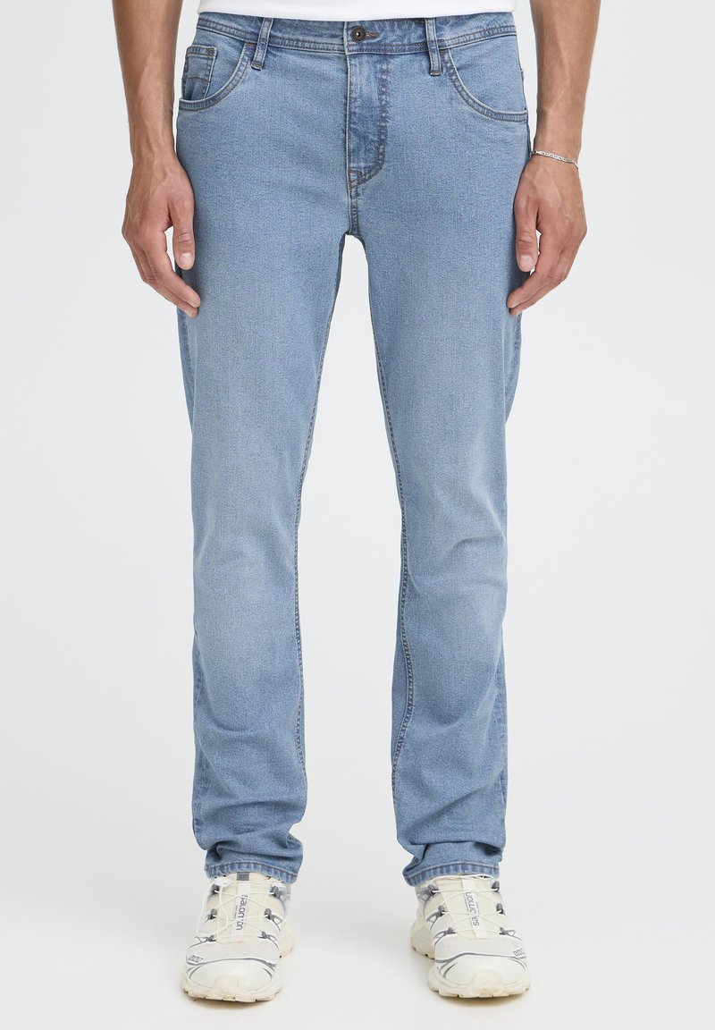 Gaiši zili džinsa džinsi ar taisnu piegriezumu, pieciem kabatām, pogu aizdari un vieglu izbalējumu papildus tekstūrai.