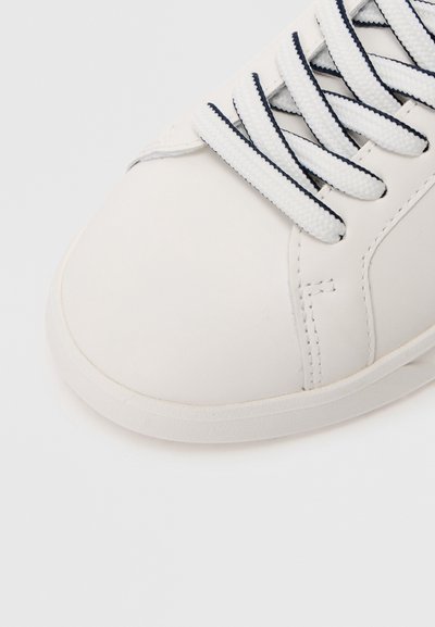 Sapatilha branca de couro com superfície texturizada, apresentando atacadores de realce azul escuro e sola de borracha lisa. Design com biqueira arredondada para conforto.
