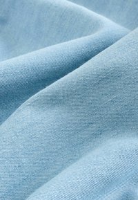 Light blue fabric with a smooth texture and visible weave pattern, displaying soft folds and slight shine. Suitable for apparel or upholstery.