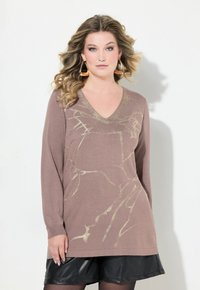 Pull marron à col en V, à manches longues, avec un motif abstrait doré. Texture douce, coupe ample, associé à une jupe en simili cuir noire.