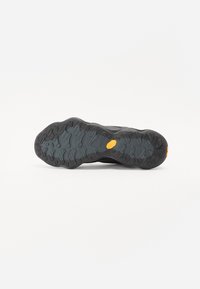 Musta sportlik jalatsite välistald, millel on tekstuurne kumm ja silmapaistev tallakujundus, ning küljes kollane Vibram logo.