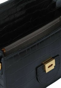 Borsa a mano in pelle nera con texture a coccodrillo, hardware dorato e scomparto con zip; forma rettangolare con chiusura a pattina.