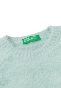 Maglione blu chiaro e morbido con scollo rotondo. Presenta un'etichetta verde con la scritta "UNITED COLORS OF BENETTON." Tessuto morbido e design a maglia larga.