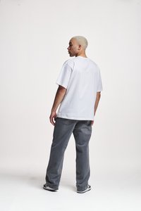 Hvit bomulls t-skjorte med korte ermer, avslappet passform, sammen med grå denimjeans. Antrekket inkluderer svart-hvite sneakers.