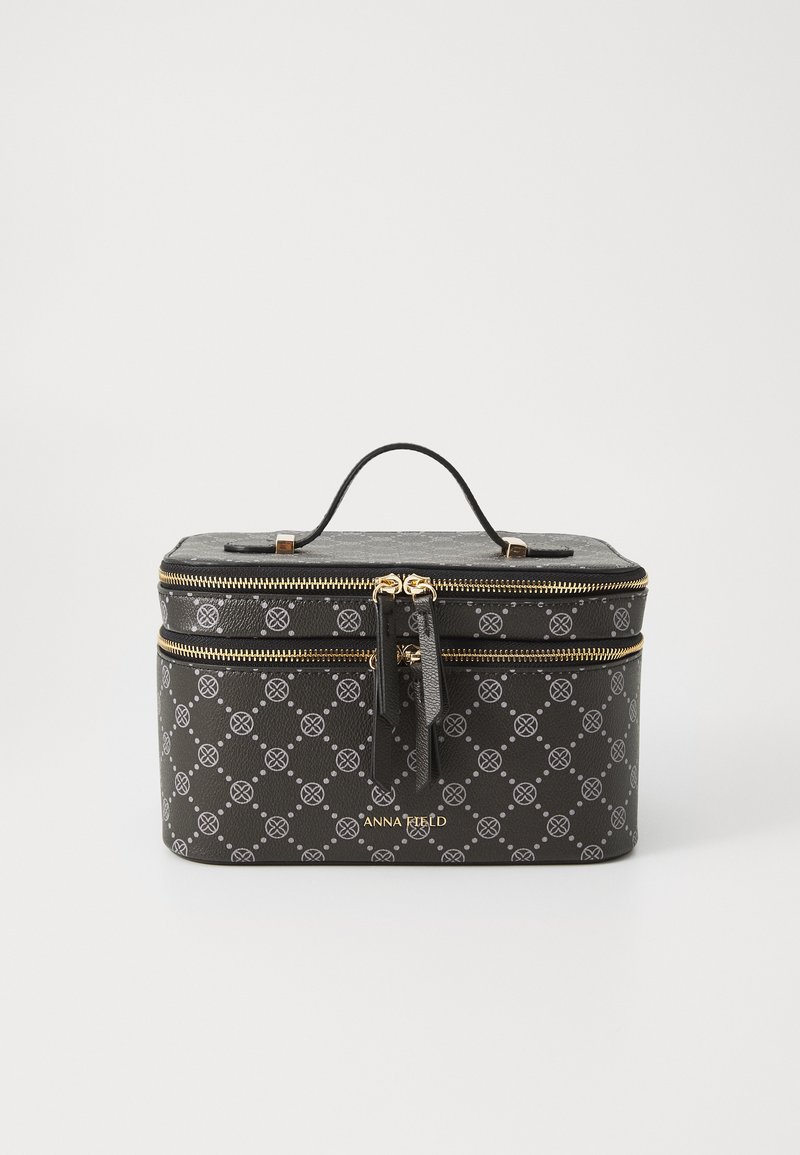 Necessaire preta com zíperes dourados, apresentando um exterior estampado e uma alça superior para facilitar o transporte. O nome da marca é visível na frente.