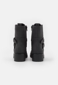 Černé kotníkové boty vyrobené z hladké kůže, se dvěma bočními zipy a spona na vnější straně, s robustním podpatkem.