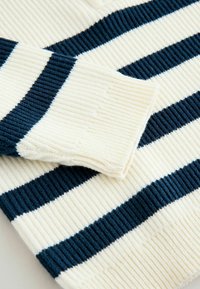 Maglione lavorato a maglia con strisce alternate color crema e blu navy, con trama a coste e dettaglio del polsino risvoltato.