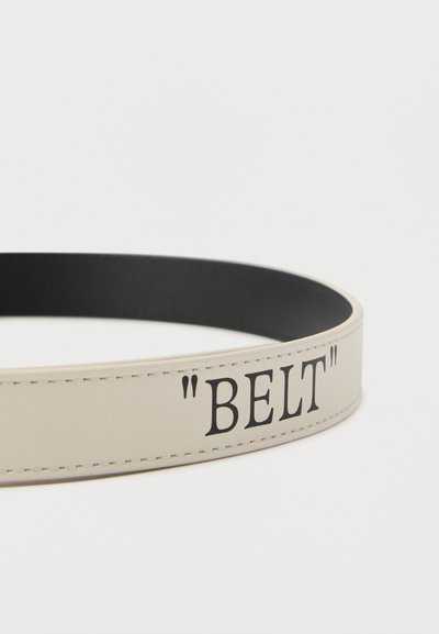 Λευκή δερμάτινη ζώνη με μαύρο εσωτερικό και τη λέξη "BELT" τυπωμένη με μαύρα γράμματα και εισαγωγικά στην εξωτερική πλευρά.
