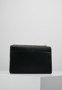 Svart läderhandväska med texturerad yta, rektangulär form, guldkedjearmband och en bakficka. Enkel och modern design.